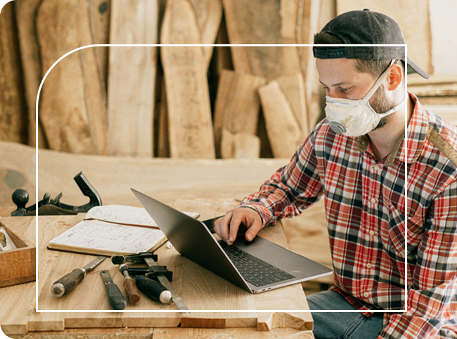 Carpenter working on their laptop in their workshop